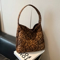 Vintage hobo-schoudertas met luipaardprint van imitatiesuède op een decoratief boek - Bruin