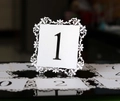 Detailed macro view of laser-cut lace wedding table number cards on glossy surface - White