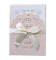 Detail of pink laser-cut wedding invitation with lace patterns and cream ribbon bow - Nude Pink