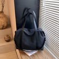 Borsa tote minimalista in tela nera con manici lunghi su gradini di legno al sole - Nero