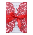 Macro shot of red laser-cut floral wedding invitation with silk bow and white inner card - Pearlescent Red