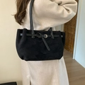 Minimalistische zwarte suède-look tote bag met gesp over de schouder van een vrouw - Zwart