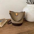 Detail van de vintage olijfgroene emmer tas met gouden metalen embleem op een houten tafel - Mocha
