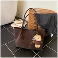 Detail of dark brown suede tote bag with a small bear pendant in a cozy lifestyle setting - With Charm / Brown