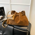 Caramel brown suede bucket bag with drawstring closure and mini charm pouch on leather bench - Brown No Pendant