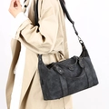 Bolso tote vintage gris oscuro con remaches y logo metálico llevado por una modelo - Negro
