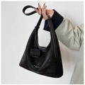 Detailed view of black matte leather tote bag with branded charm and handle strap - Ebony