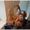 Detail of vintage brown tote bag with dual buckle pockets and plush dog charm - With Charm / Yellow Brown