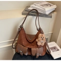 Detail view of brown vintage tote bag with metal buckle pockets and plush bear charm - With Charm / Coffee