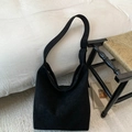 Primer plano del bolso hobo de ante negro con textura en un entorno hogareño minimalista - Negro