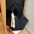 Black tote bag with diamond weave texture and decorative scarf on a wooden table - Black