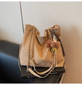 Detail shot of tan suede tote bag featuring a gold chain strap and bear charm on a black sofa - Khaki with Pendant