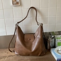 Close-up of brown leather hobo tote bag with decorative flap on a wooden tabletop - Brown No Pendant