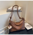 Dettaglio di una borsa tote in pelle marrone con spalline annodate e ciondolo a forma di cane - Marrone con ciondolo