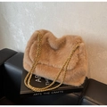 Détail du sac bandoulière en fausse fourrure marron avec chaîne dorée sur un canapé en cuir - Khaki