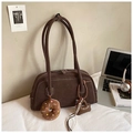 Detail view of brown faux suede Boston bag with donut and heart bag charms on a desk - Coffee With Pendant