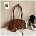 Brown suede baguette bag with donut charm shown in a minimalist lifestyle setting - Brown with Pendant