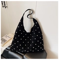 Schwarze Hobo-Tasche aus Wildleder mit Nieten neben einem Kunstbuch auf Lederbank - Schwarz