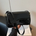 Modern black glossy patent leather crossbody shoulder bag with golden buckle detail - Black