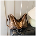 Detail of vintage brown tote bag with metallic texture and brass hardware on books - Brown
