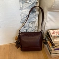 Detail einer dunkelroten Lederhandtasche im Vintage-Stil mit niedlichem Hundeanhänger - Mit Anhänger / Burgunderrot