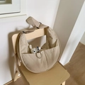 Detail der beige Nylon-Halbmondtasche mit verstellbarem Gurt und weißem Bärenanhänger - Cremeweiß