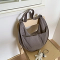 Taupefarbene Halbmond-Schultertasche aus Nylon mit breitem Gurt auf einem Stuhl - Grau