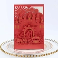 Close-up of red laser-cut wedding invitation featuring a castle and carriage design - Red