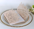 Close-up of laser-cut floral pink wedding invitation with intricate rose patterns - Pink
