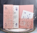 Close-up of pink laser cut wedding invitation set with intricate lace floral envelope design - Pink
