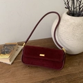Bolso vintage de gamuza color burdeos con herrajes dorados sobre un banco de madera - Burdeos