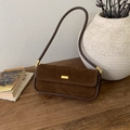 Detail der dunkelbraunen Vintage-Wildleder-Tasche mit Goldverschluss auf Holzoberfläche - Braun