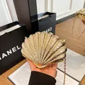 Elegante goldene Abendtasche in Muschelform mit Metallstruktur und Kettenriemen - Hellgold