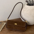 Bolso baguette de ante marrón oscuro vintage con hebilla dorada sobre madera - Marrón