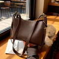 Dark brown leather shoulder bag with gold buckle and soft plush charm in a cafe setting - Coffee with Pendant