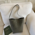 Minimalist olive green leather bucket bag on a white sofa with artistic book - Green Without Pendant