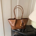 Vintage brown leather tote bag with colorful beaded tassel on a black stool - With Charm / Brown