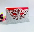 Macro detail of laser-cut silver glitter mask invitation with a festive red insert card - Glitter Silver