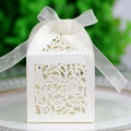 Macro shot of white laser-cut rose wedding favor box with an elegant ribbon bow - Ivory