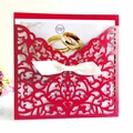 Detail der roten Laser-Cut Hochzeitseinladung mit weißer Satinschleife und Goldring-Motiv - Perlrot