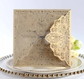 Vista macro di un invito a nozze in pizzo dorato tagliato al laser su piatti eleganti - Beige Oro