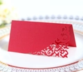 Detail of red laser-cut place card with elegant floral lace pattern on a white plate - Pearlescent Red
