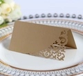 Detail view of a laser-cut gold wedding place card on a white decorative porcelain plate - Beige Gold