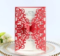 Detail of red laser-cut butterfly invitation card with white insert on elegant tableware - Red