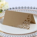 Elegant gold laser-cut wedding place card with intricate floral pattern on white plate - Beige Gold