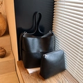 Matte black leather bucket bag set with matching inner pouch on a wooden window sill - Black