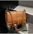 Detailed macro view showing the brown lychee grain texture and gold bar clasp on the bag - Brown