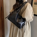 Bolso tote retro de cuero PU brillante negro con correa ancha mostrado en un modelo - Negro