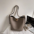 Sac seau bandoulière beige foncé avec fermoir doré sur une surface blanche - Gris