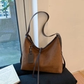 Detailansicht der braunen Wildleder-Beuteltasche mit Quastenanhänger und Ledergurt - Braun